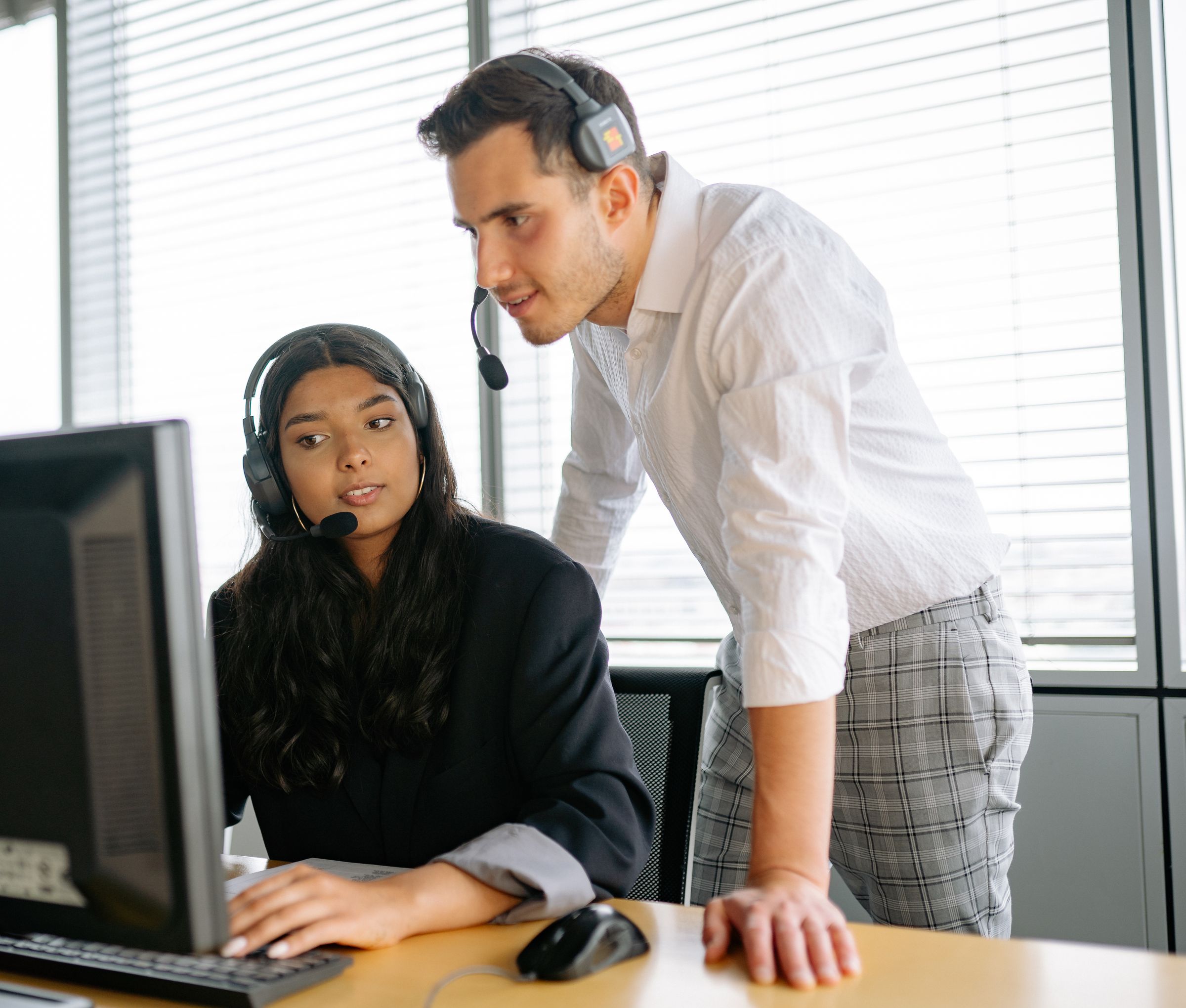 Two colleagues working together at a computer — illustrative stock photograph
